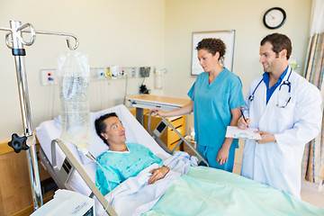 Image showing IV Bag On Rod With Medical Team Looking At Patient