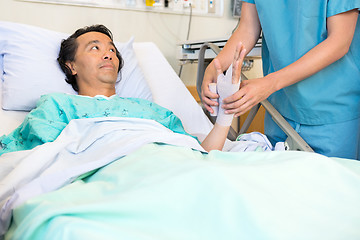 Image showing Patient Looking At Nurse Putting Bandage On Hand