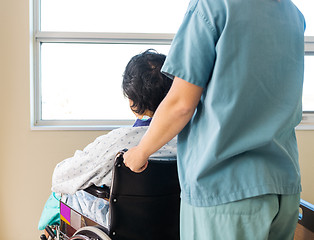 Image showing Patient Sitting On Wheelchair While Nurse Assisting Him At Windo