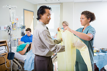 Image showing Nurse Assisting Doctor In Wearing Operation Gown At Hospital