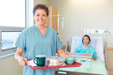 Image showing Nurse Holding Breakfast Tray With Patient Lying On Hospital Bed