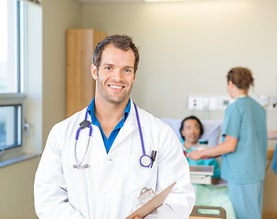 Image showing Doctor Smiling While Nurses Examining Patient In Hospital