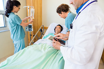 Image showing Doctor Using Digital Tablet With Nurses Examining Patient In Hos