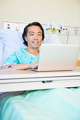 Image showing Happy Male Patient Using Laptop On Hospital Bed