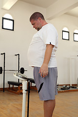 Image showing man with overweight on scales in gym