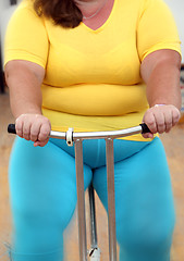 Image showing overweight woman exercising on bike simulator 