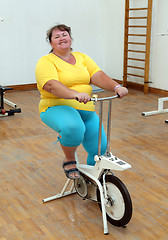 Image showing overweight woman exercising on bike simulator