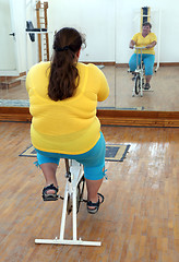 Image showing overweight woman exercising on bike simulator