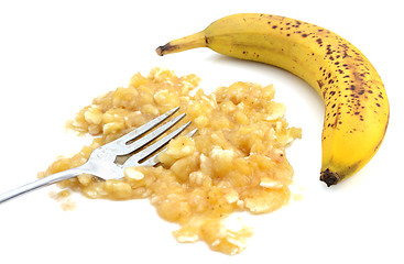 Image showing Closeup of mashed banana with fork and an unpeeled fruit