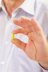 Image showing Senior adult man holds medicine capsule 