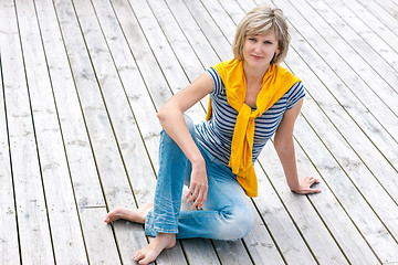 Image showing Woman sitting on the weathered wooden floor