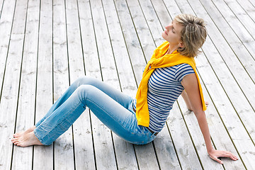 Image showing Woman sitting with closed eyes on wooden floor