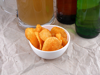 Image showing Beer bottle and potato chips on white plate