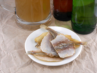 Image showing fish on white plate and beer bottle