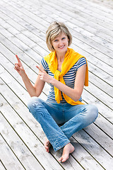 Image showing Woman sitting on the weathered wooden floor