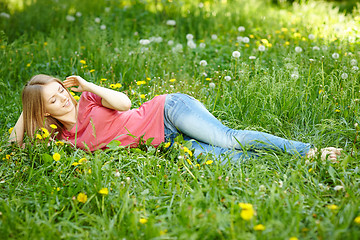 Image showing Spring girl lying on the field of dandelions