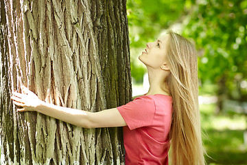 Image showing Female hugging a tree, looking up