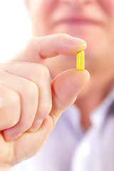 Image showing Senior adult man holds medicine capsule