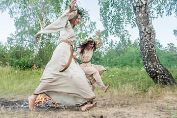 Image showing Beautiful women jumping through fire