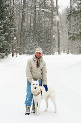 Image showing Woman with a dog on a walk in the woods during a snowfall