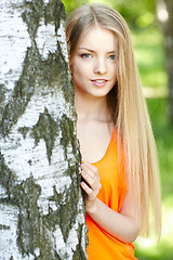 Image showing Beautiful female peeping from behind tree