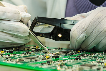 Image showing Woman in antistatic gloves holding pincette and magnifier