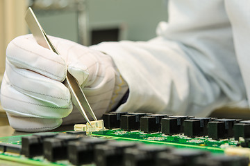 Image showing Female hand holding tweezers and installing connector on PCB