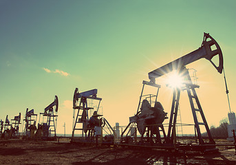 Image showing oil pumps silhouette against sun - vintage retro style