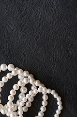 Image showing White pearls on the black silk as background