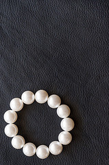 Image showing White pearls on the black silk as background