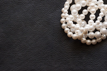 Image showing White pearls on the black silk as background