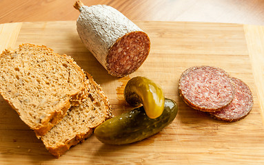 Image showing Salami slices with pickles on wood background 