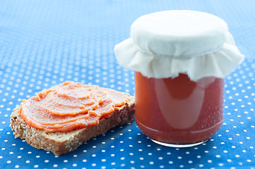 Image showing Slice of bread with quince jam and a jar of homemade jam from a quince