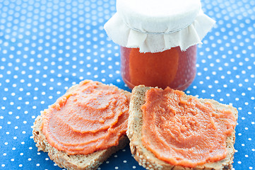 Image showing Slice of bread with quince jam and a jar of homemade jam from a quince