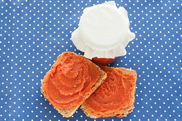 Image showing Slice of bread with quince jam and a jar of homemade jam from a quince