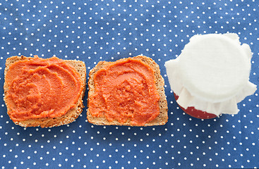 Image showing Slice of bread with quince jam and a jar of homemade jam from a quince