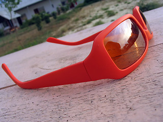 Image showing bright orange sun glasses lying on the wooden table