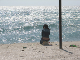 Image showing The girl in loneliness sits in the afternoon at sea coast