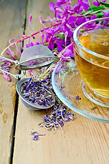 Image showing Herbal tea in cup of fireweed with a strainer on board