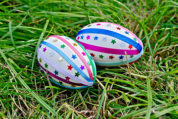 Image showing Easter eggs with ribbons and stars on grass