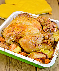 Image showing Chicken baked with vegetables on board and potholders