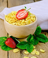 Image showing Cornflakes in wooden bowl with strawberries on board