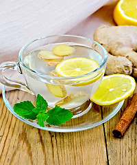 Image showing Tea ginger with lemon in a cup on board