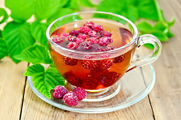 Image showing Tea with raspberry and green leaves on board