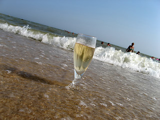 Image showing Glass of a cold champagne in warm sea waves on a beach 1