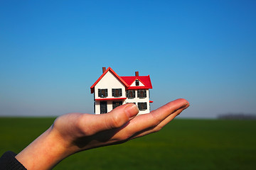 Image showing Female hand holding model of residential building