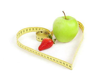 Image showing green apple with a measuring tape and heart symbol isolated