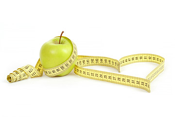 Image showing green apple with a measuring tape and heart symbol isolated