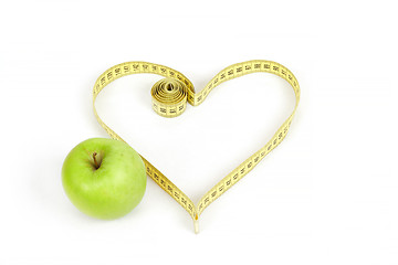 Image showing green apple with a measuring tape and heart symbol isolated