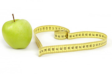 Image showing green apple with a measuring tape and heart symbol isolated